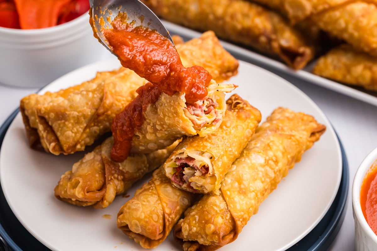 sauce spooned onto plate of egg rolls