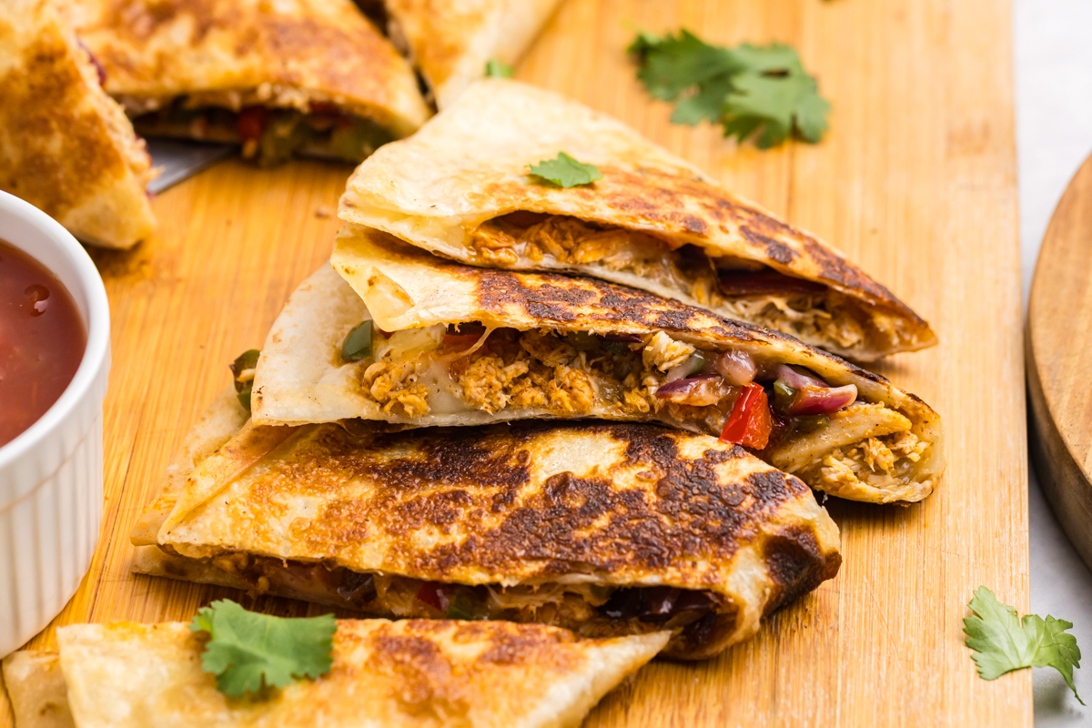 angled shot of chicken quesadilla triangles on cutting board