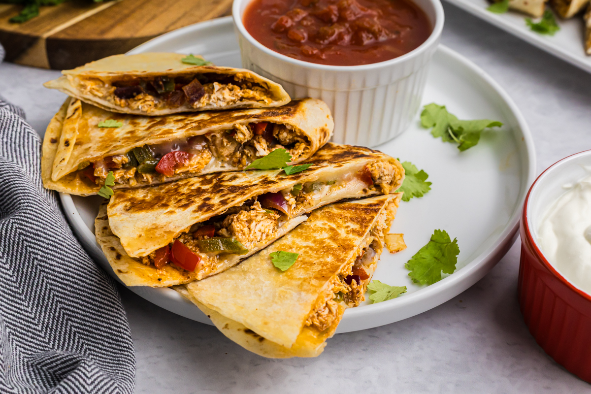 angled shot of chicken quesadilla on plate with salsa