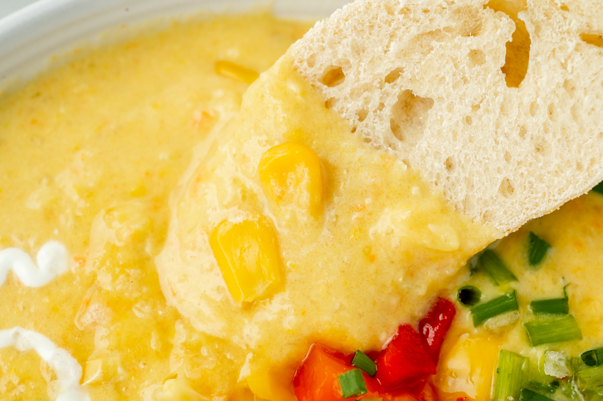 close up of bread dipping into bowl of soup