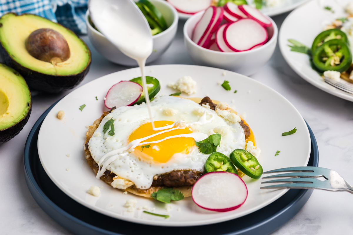 cream drizzling over huevos rancheros