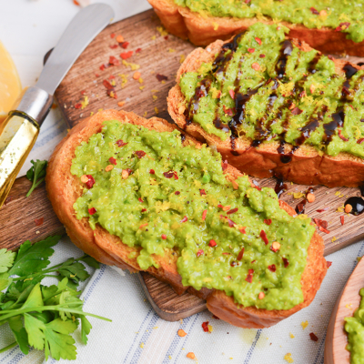close up angled shot of pea mash crostini on board