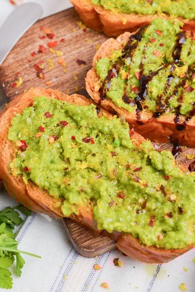 close up angled shot of pea mash crostini on board