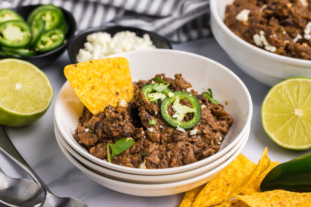 angled shot of bowl of refried beans topped with jalapeno
