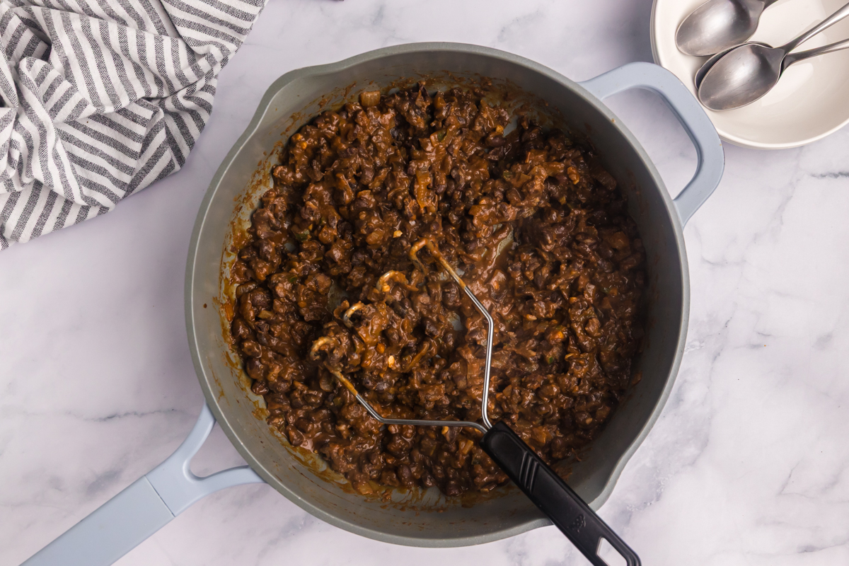 black beans in pot with masher