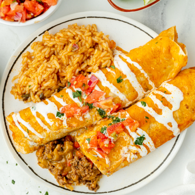 overhead shot of smothered beef burritos on plate with rice