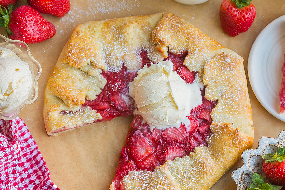 overhead shot of slice taken out of strawberry galette topped with ice cream