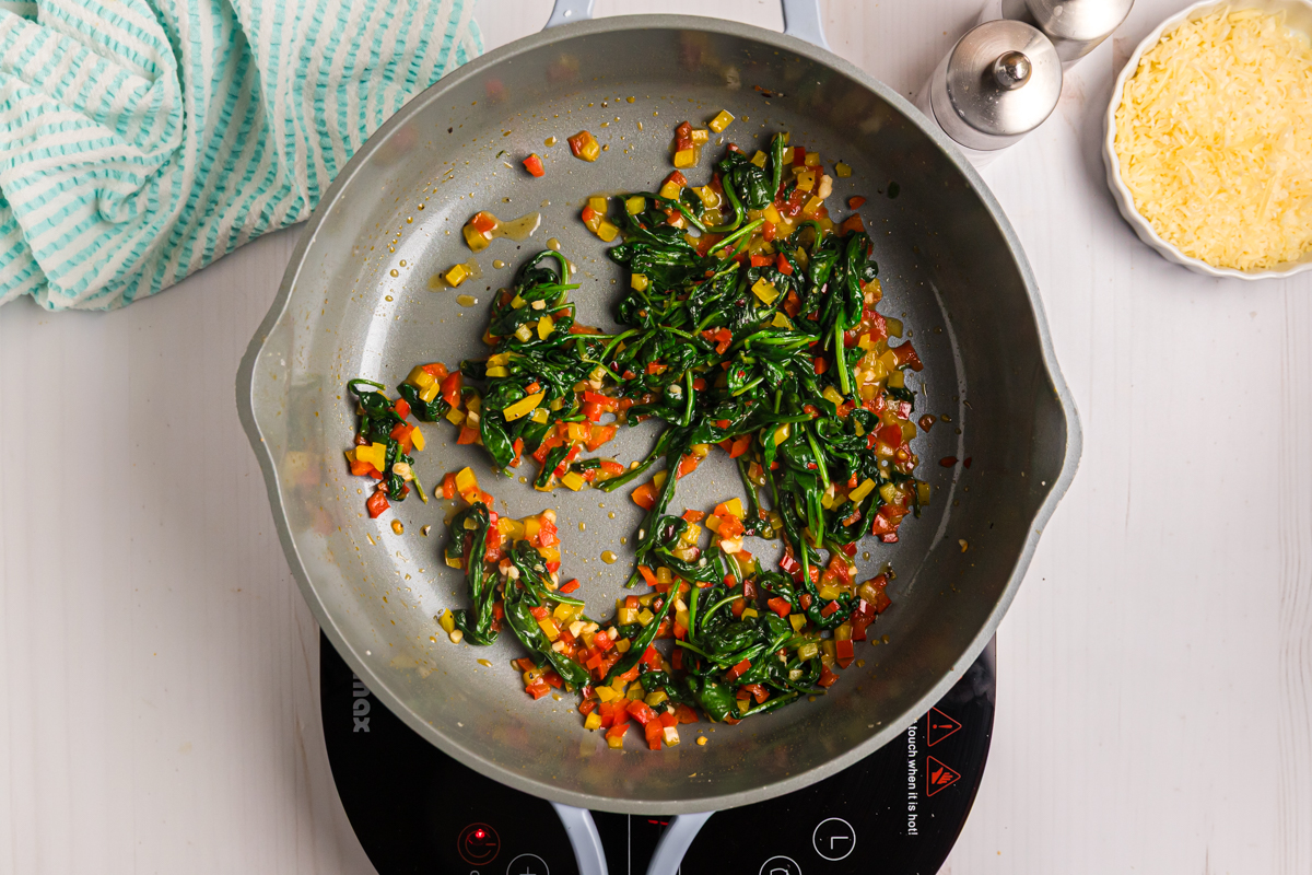 spinach and peppers cooking in pan