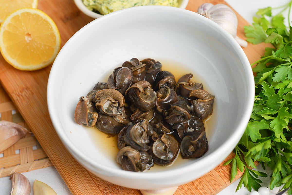 close up of canned escargot in a white bowl