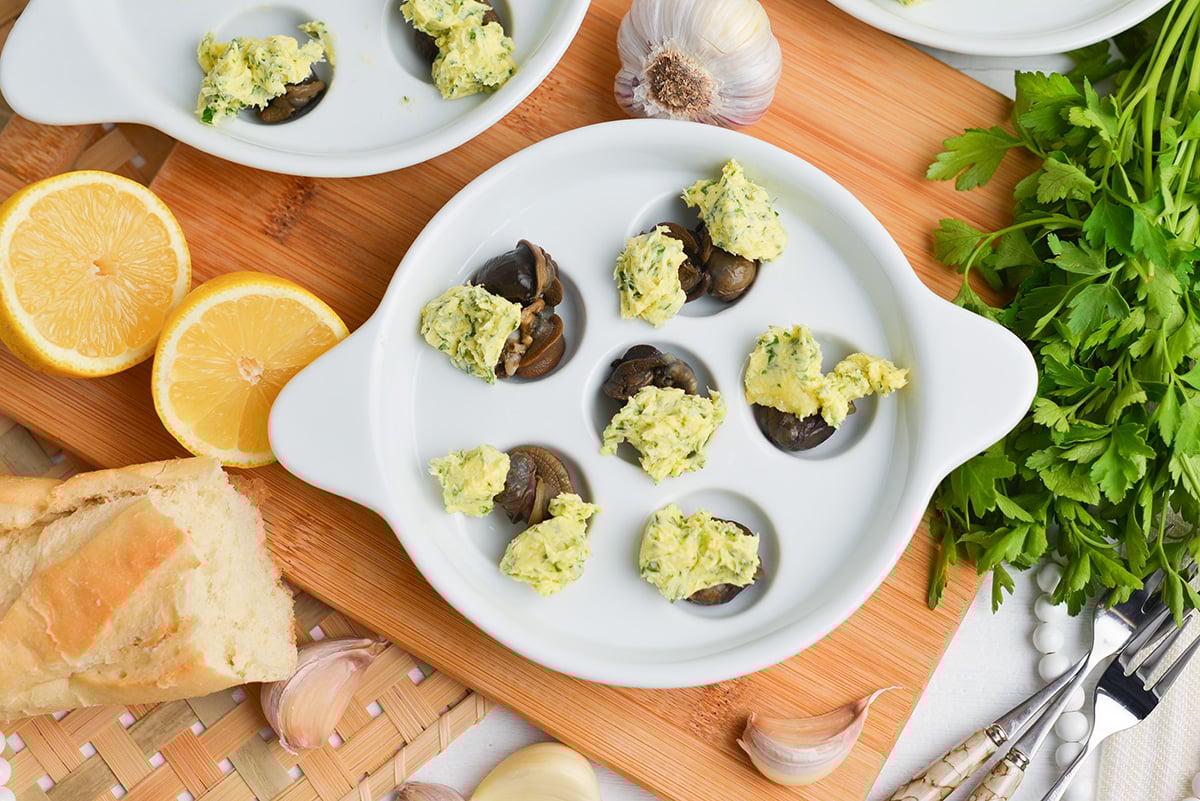 overhead of snails in an escargot dish with garlic parsley butter