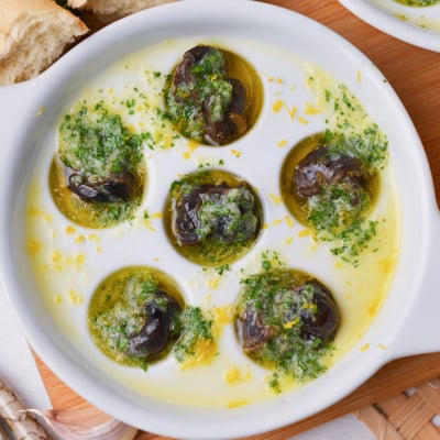 close up of snails in garlic butter in an escargot dish
