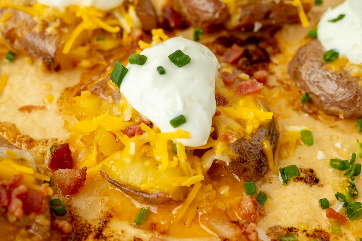 close up angled shot of smashed potato topped with sour cream