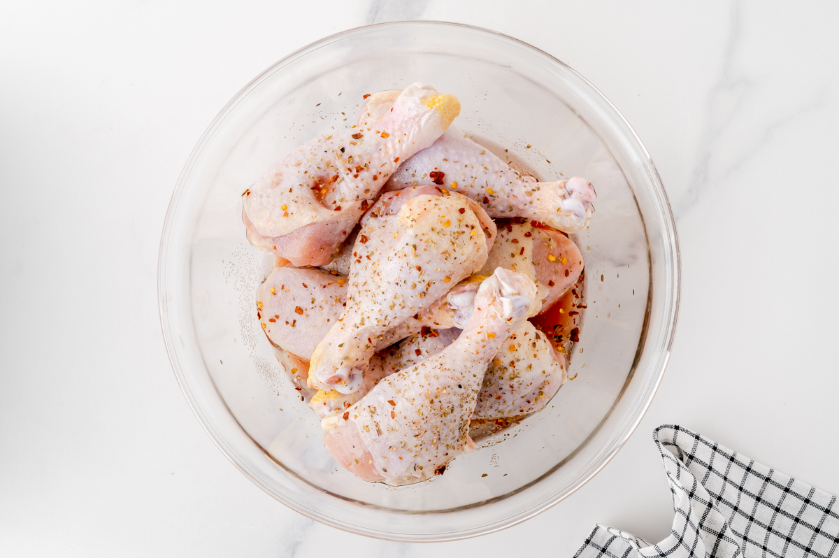 overhead shot of raw chicken in bowl with seasonings