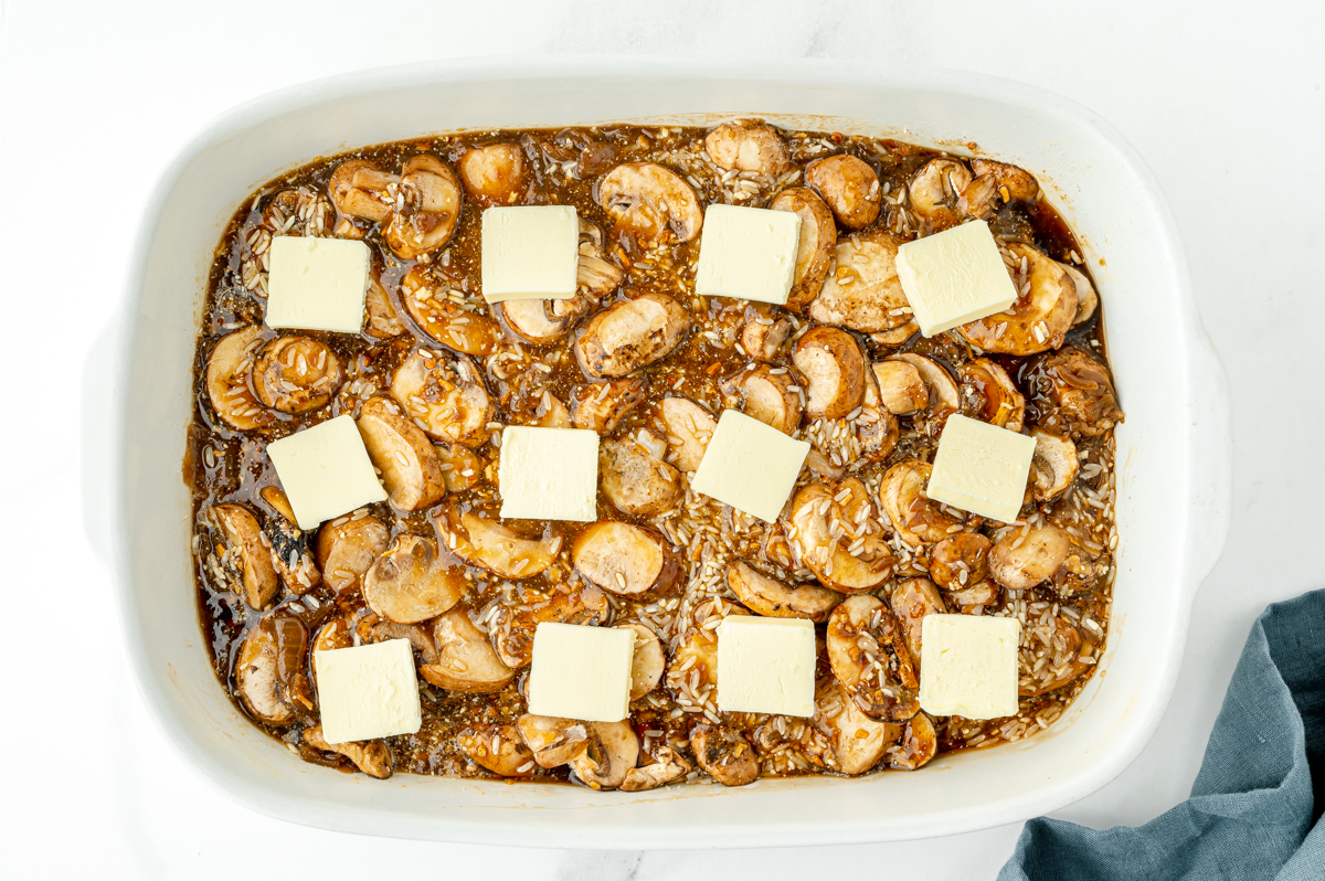 overhead shot of butter slices on pan of rice and mushrooms