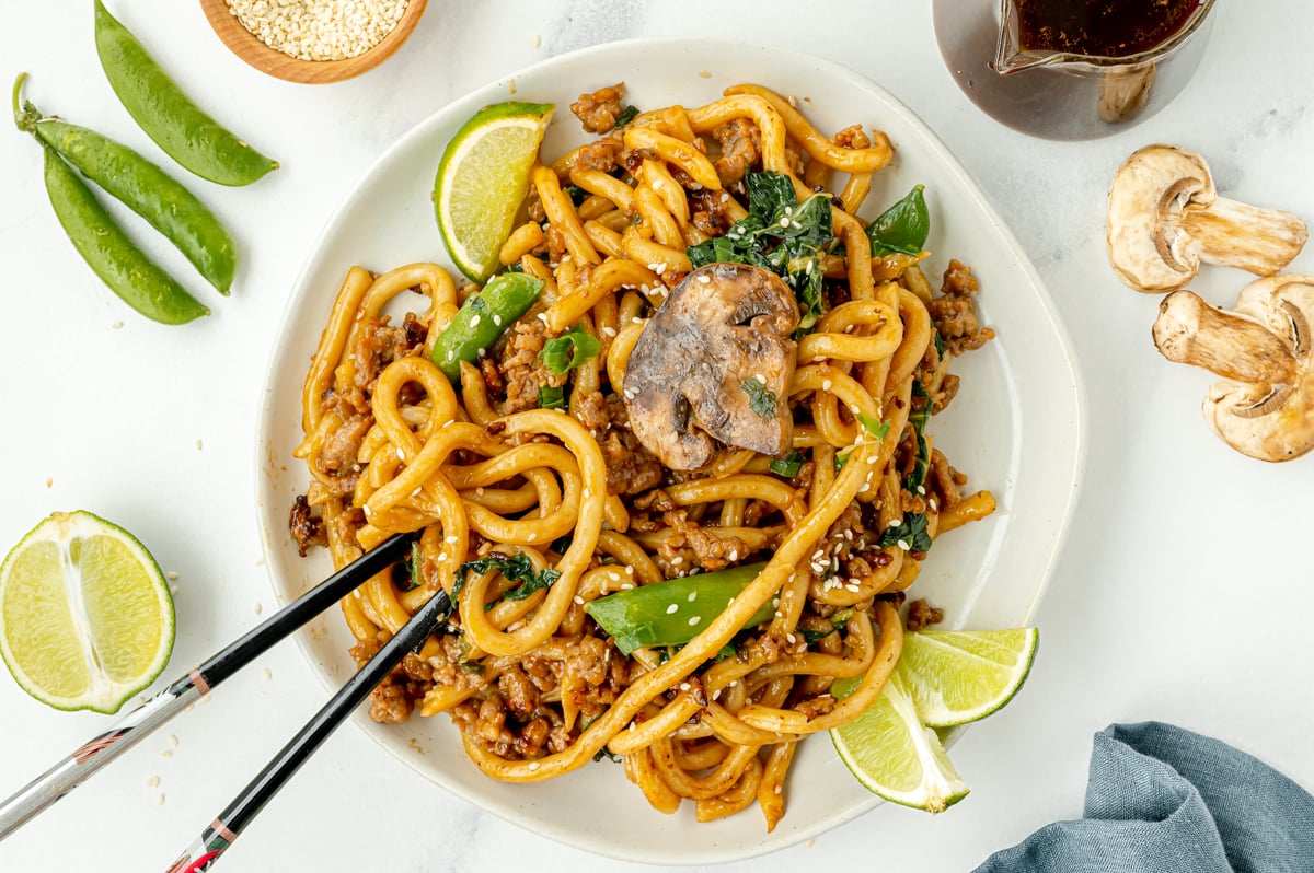 chopsticks on plate of udon noodle stir fry