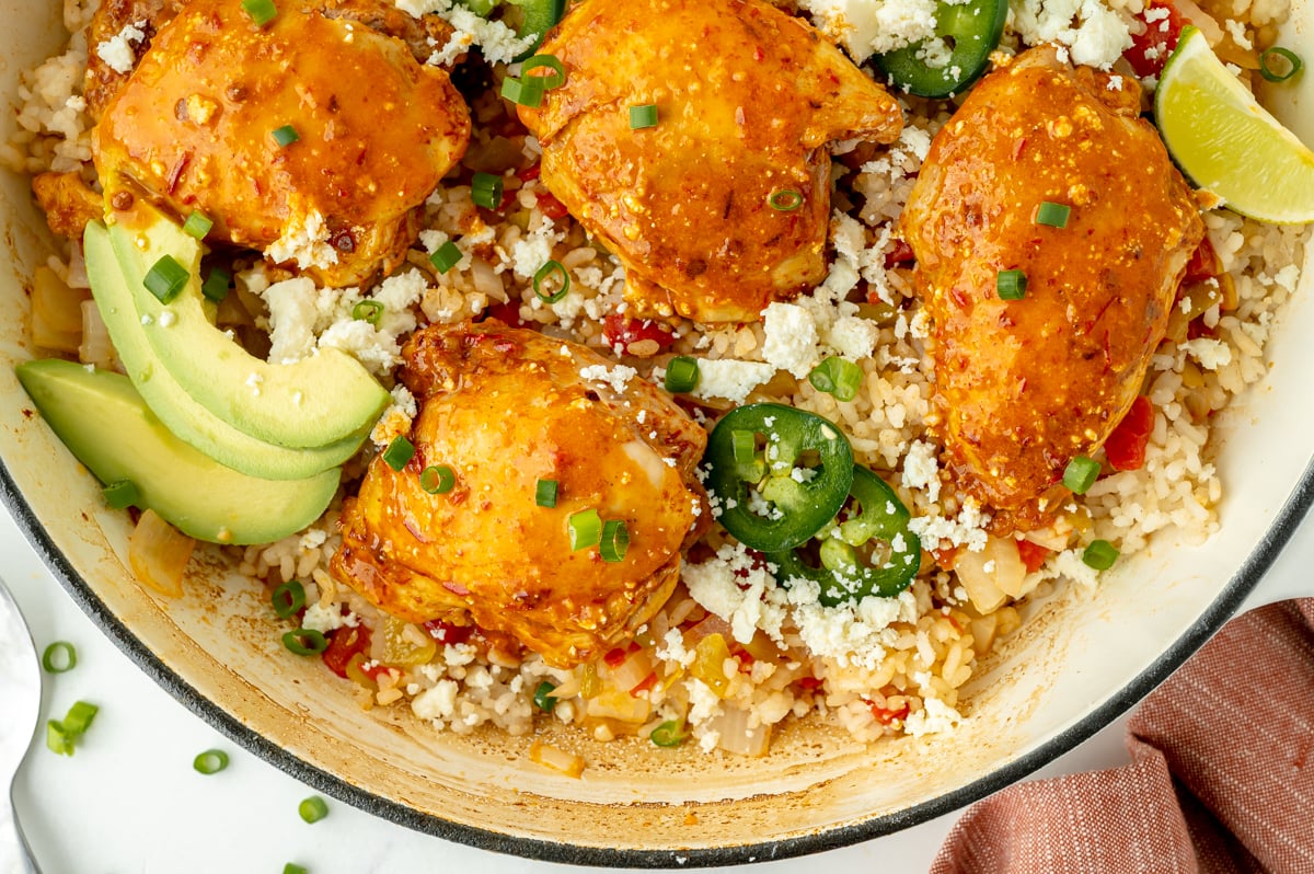 close up overhead shot of chicken, rice, avocado and jalapeno in a pan