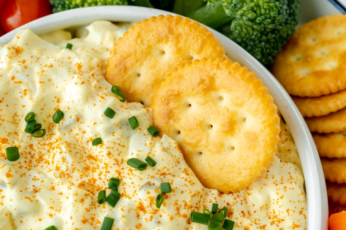 close up of crackers in bowl of dip topped with chives