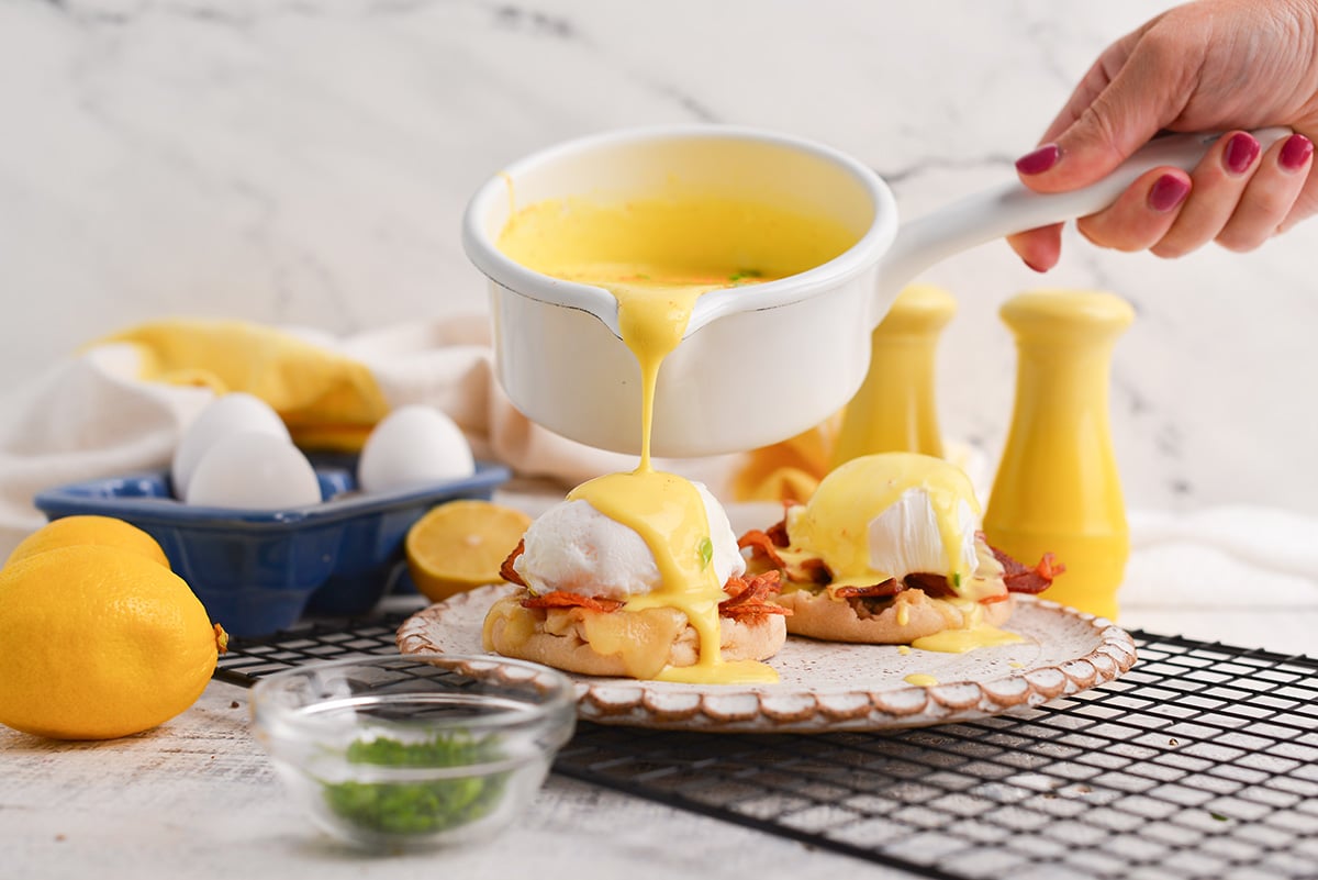 sauce pouring over eggs benedict