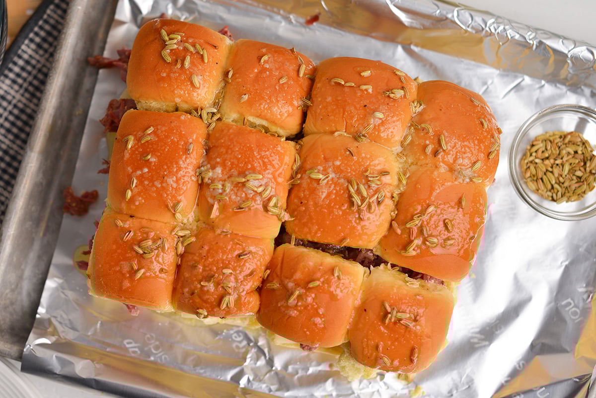overhead of fennel seeds and buttery topping on corned beef slider sandwiches