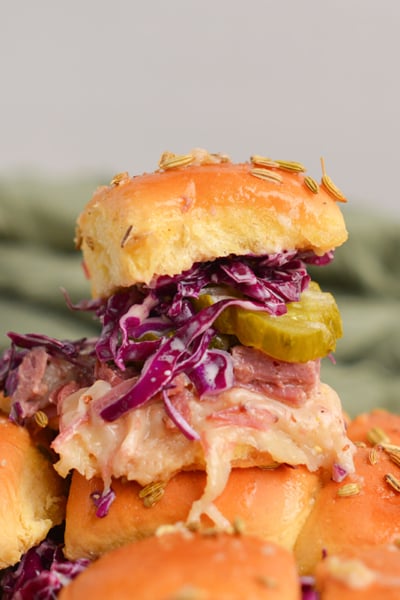 slider sandwich piled high with a pickle, coleslaw, corned beef and cheese