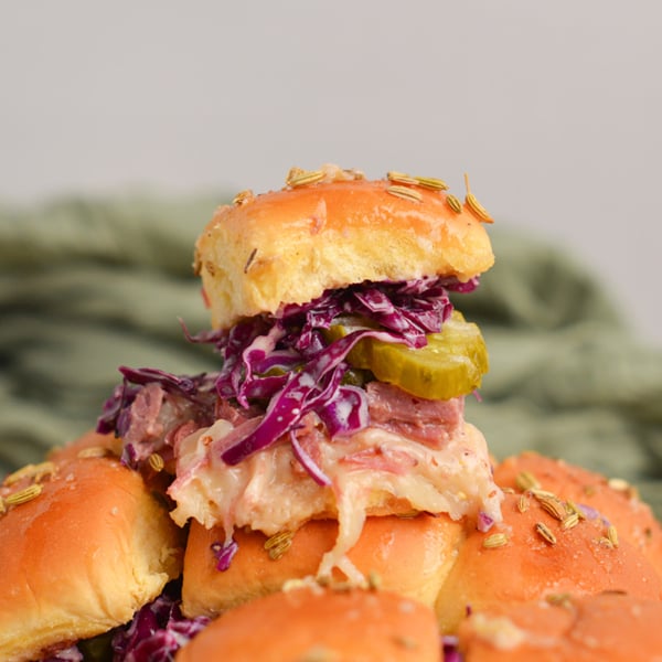 slider sandwich piled high with a pickle, coleslaw, corned beef and cheese