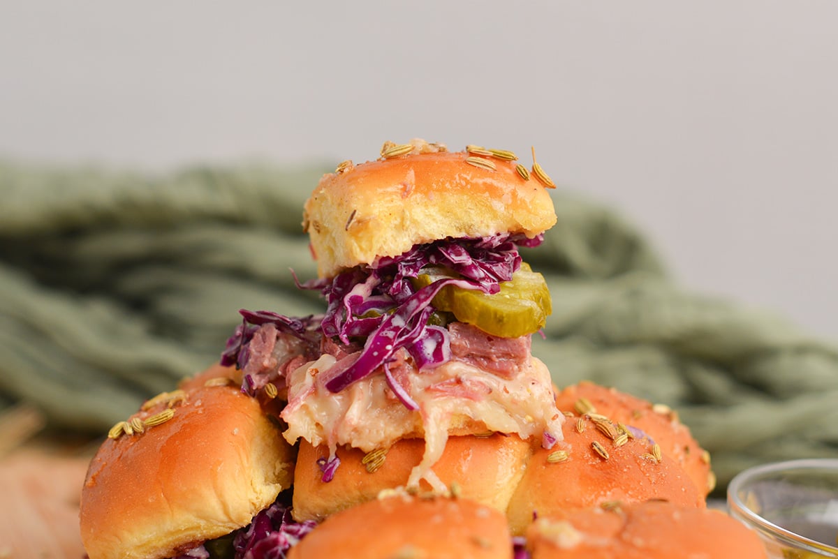 slider sandwich piled high with a pickle, coleslaw, corned beef and cheese