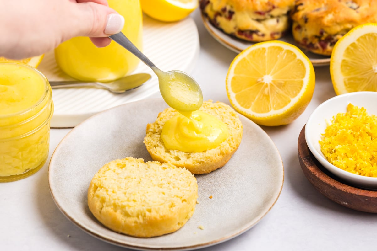 spoon adding lemon curd to biscuit