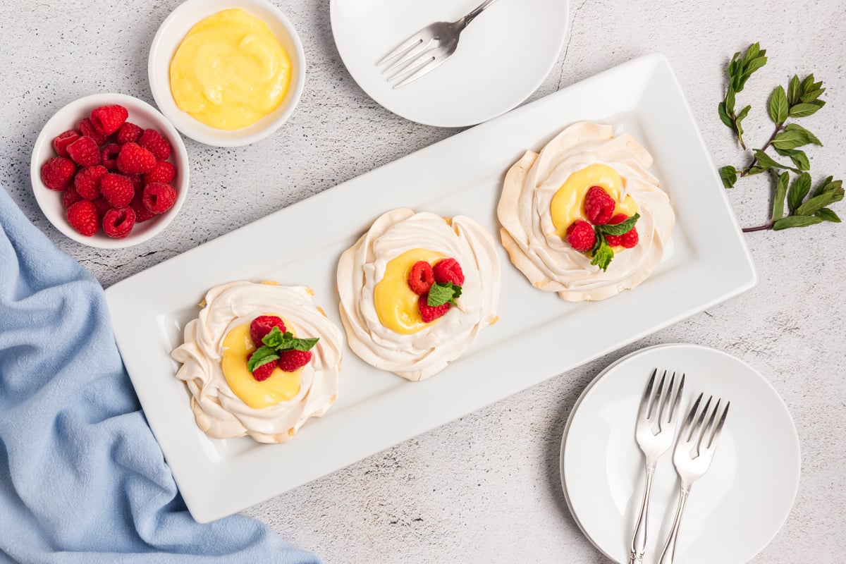 overhead shot of three mini pavlovas with lemon curd on platter
