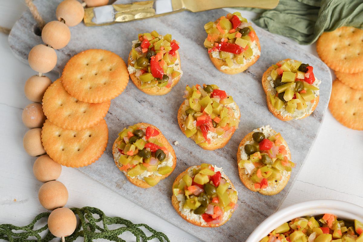 close up of green olive tapenade with soft cheese on crackers