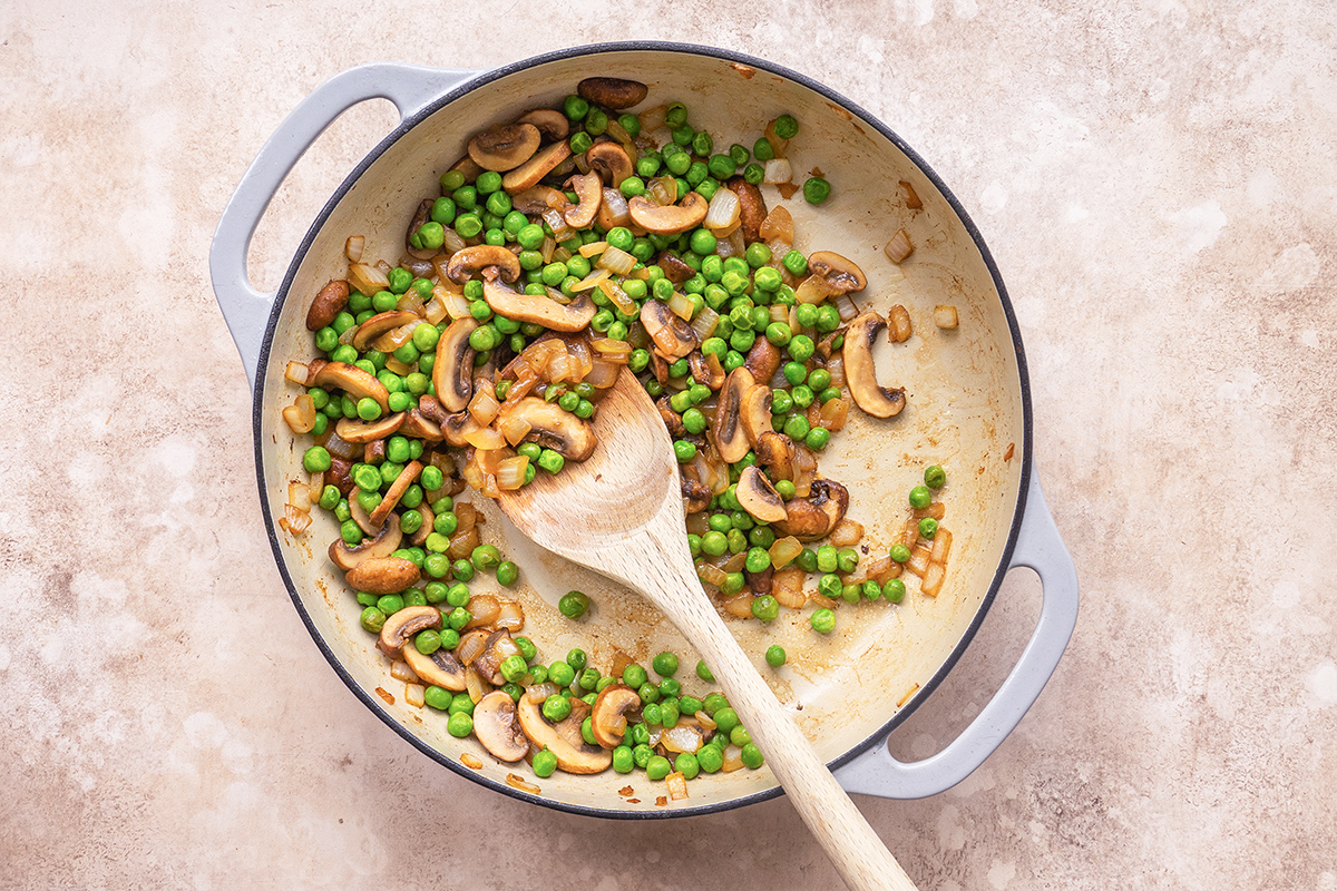 mushrooms, onions and peas saut&eacute;ed in a skillet