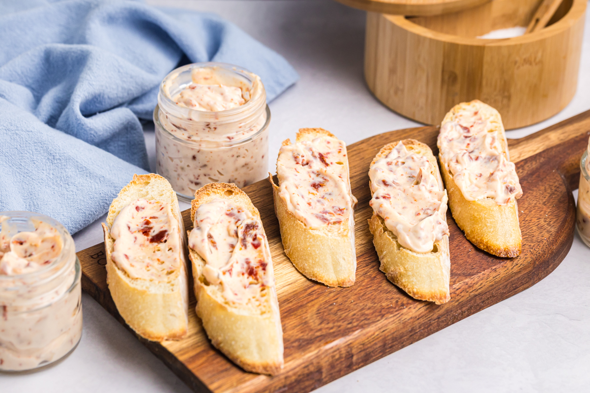 angled shot of baguette slices on wooden board with aioli on them