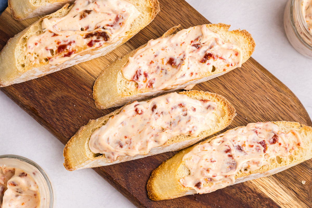 overhead shot of baguette slices on wooden board with aioli on them