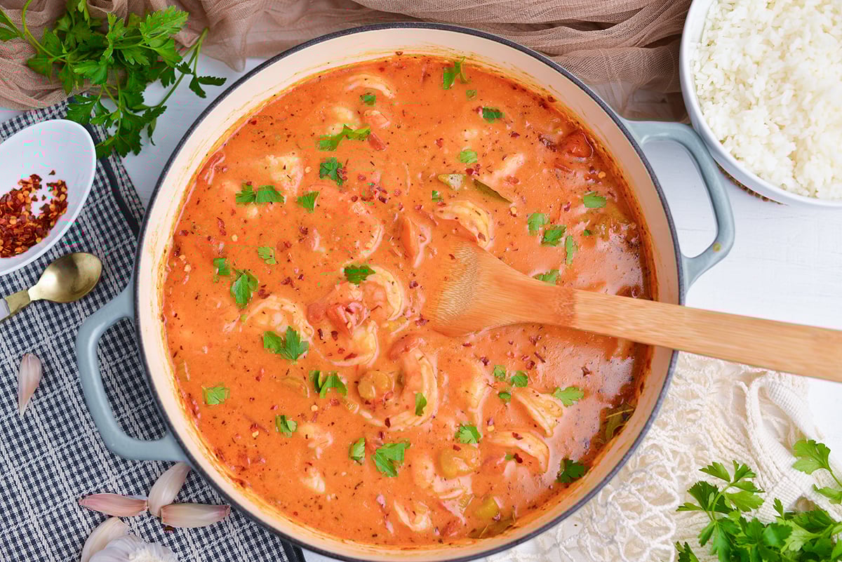 overhead of creamy shrimp creole in skillet with a side of rice