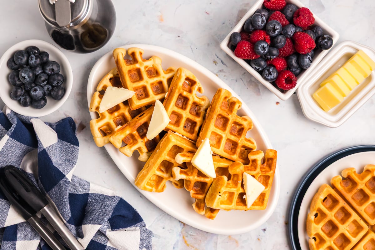 overhead shot of waffles on platter with butter and bowls of berries