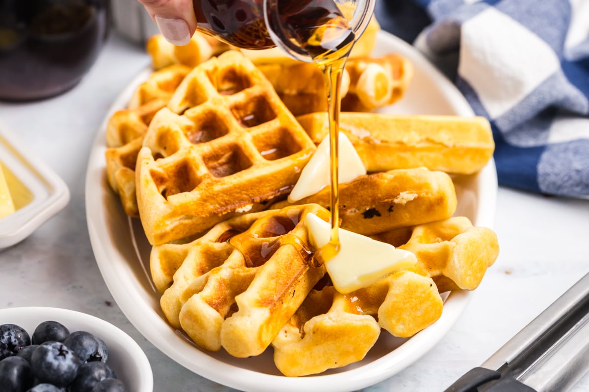 angled shot of syrup pouring over waffles