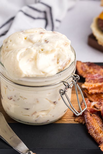 angled shot of bacon aioli on cutting board with bacon