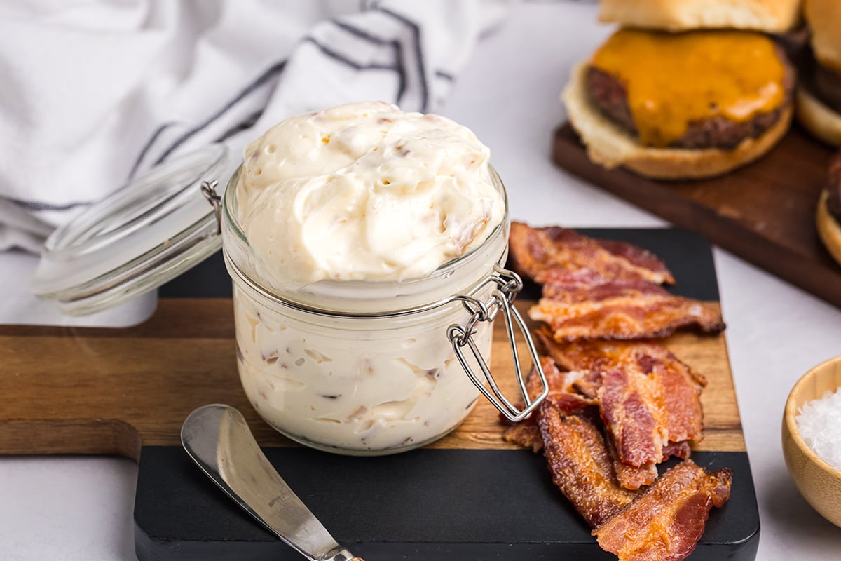 angled shot of bacon aioli on cutting board with bacon