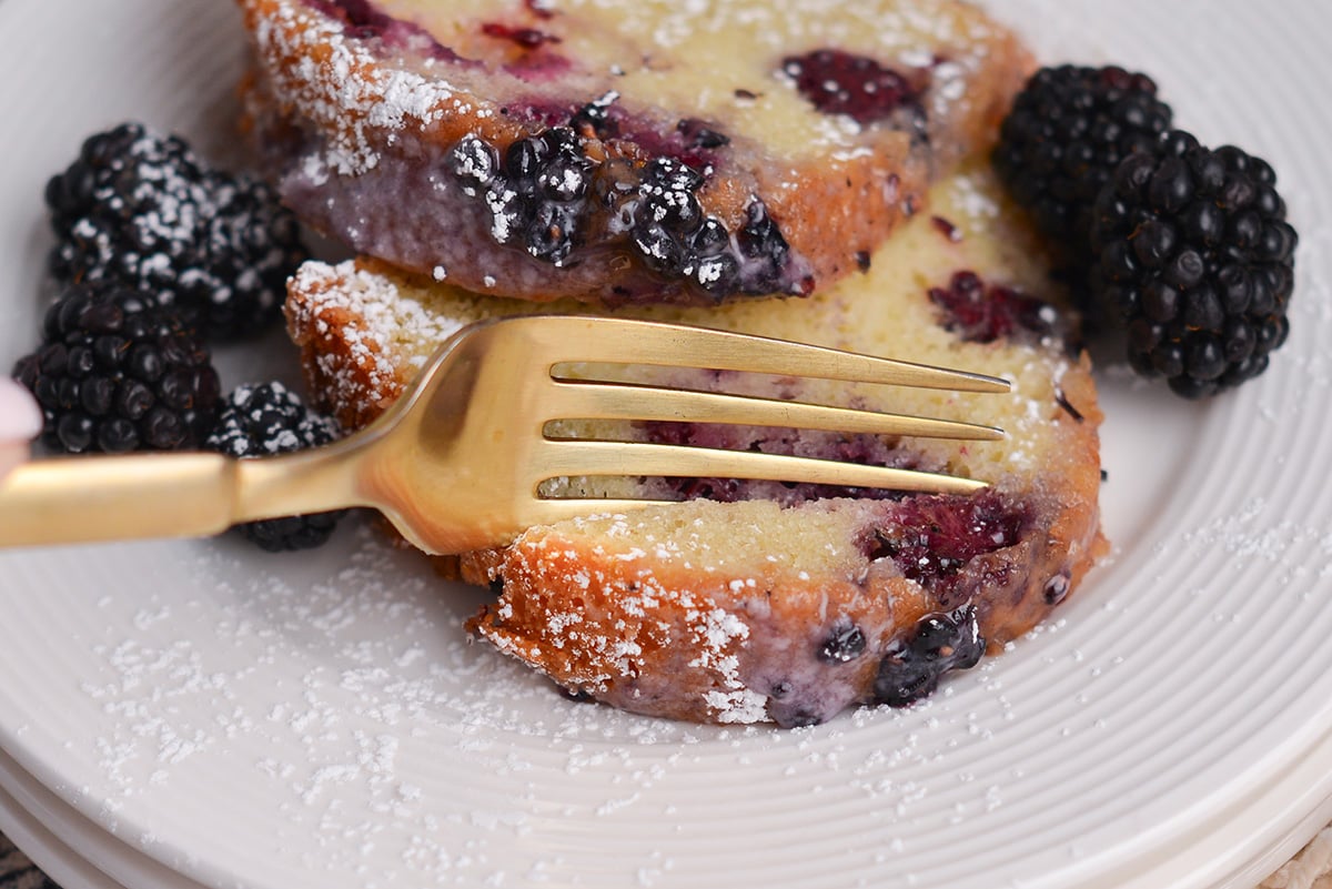 fork cutting into a tender crumb of blackberry cake