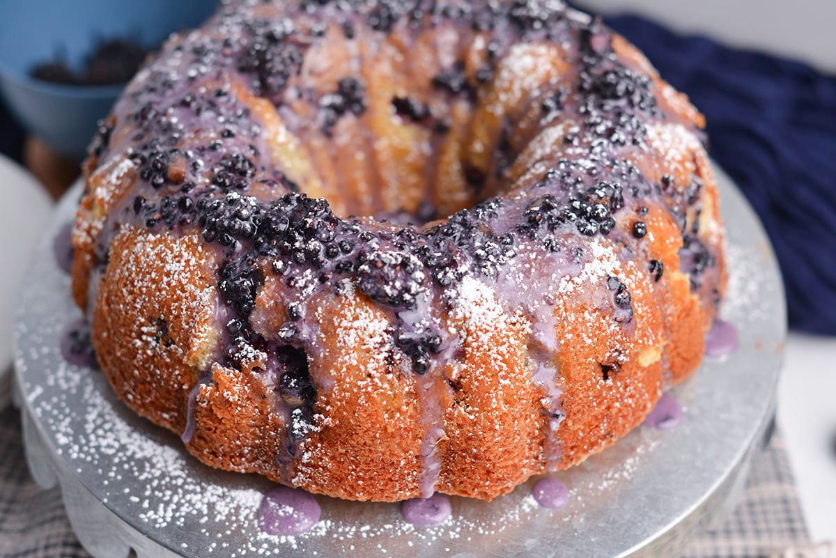 Whole blackberry bundt cake topped with blackberry icing and fresh berries
