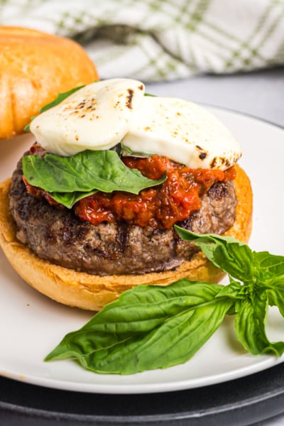 angled shot of caprese burger on plate with basil