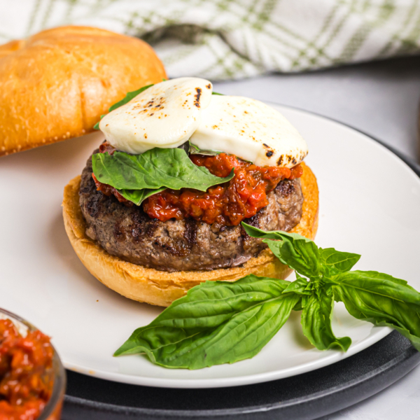 angled shot of caprese burger on plate with basil