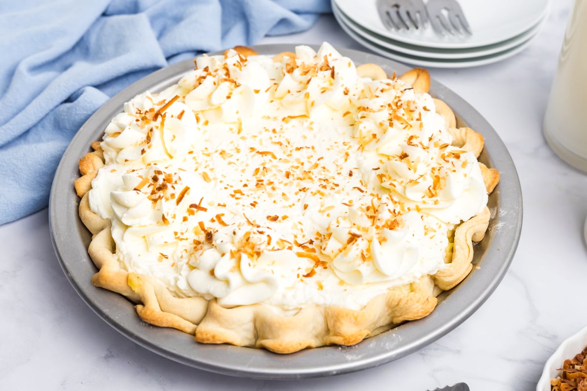 angled view of homemade coconut cream pie topped with whipped cream and toasted coconut