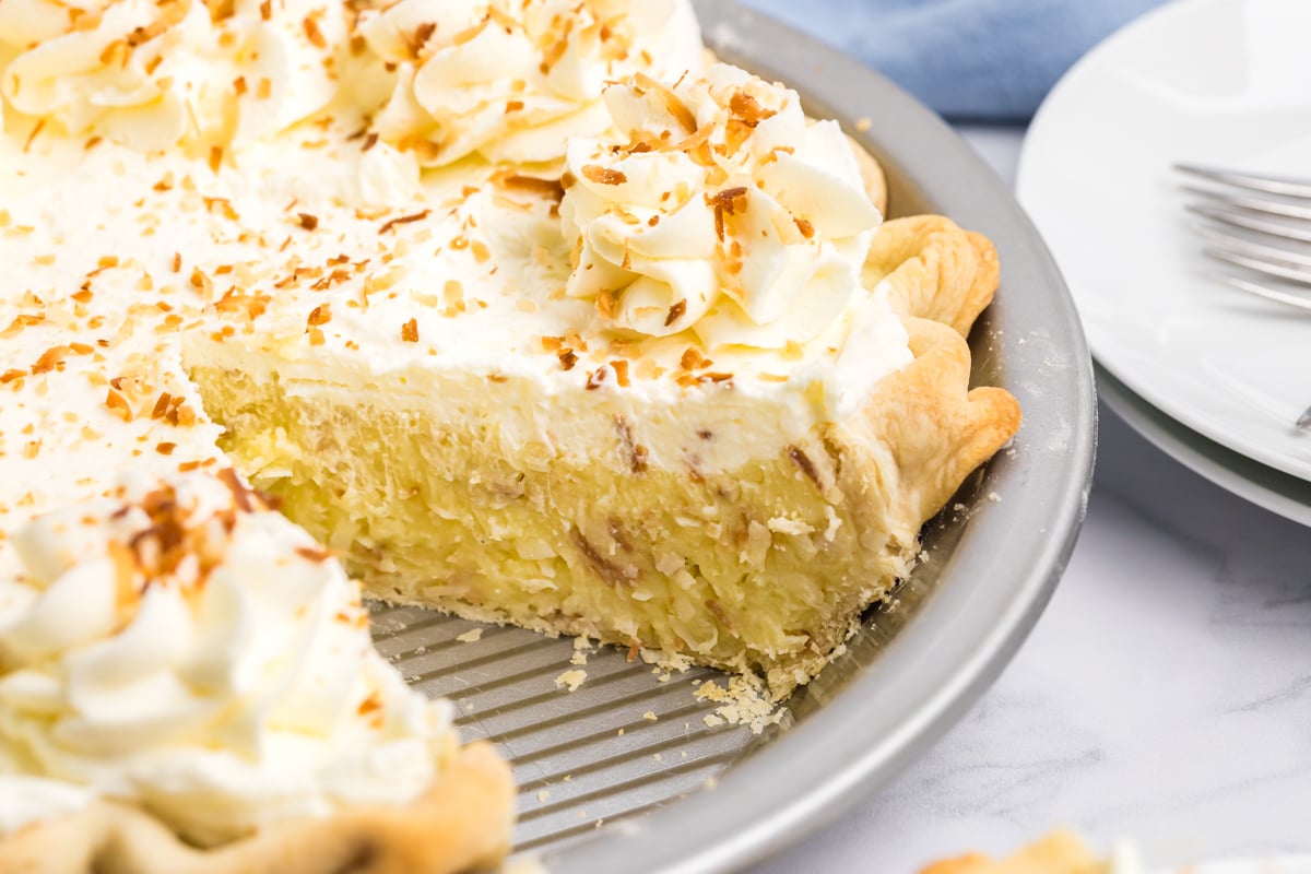 coconut cream pie with one slice removed showing creamy coconut custard filling