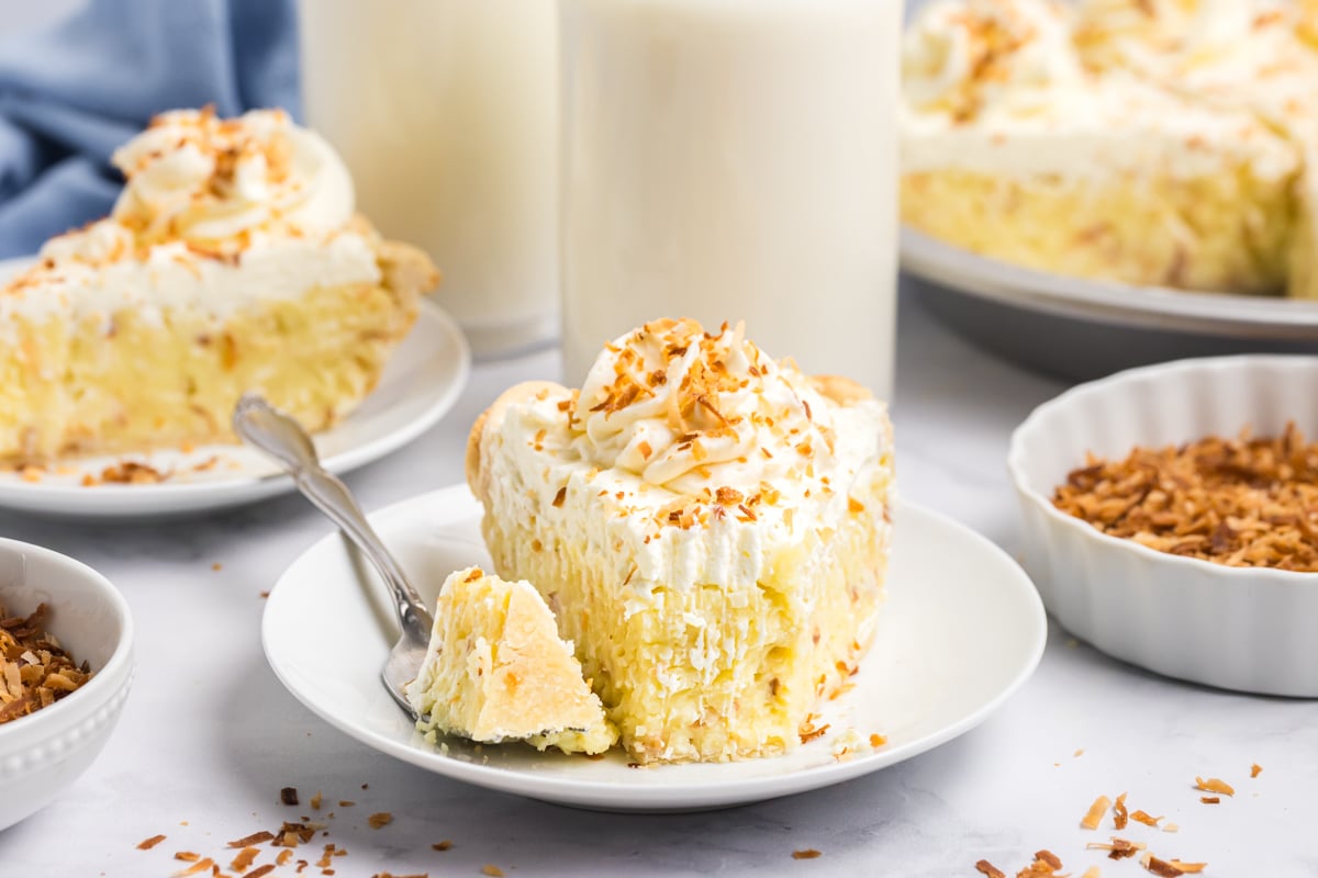 fork lifting a bite of coconut cream pie with whipped cream