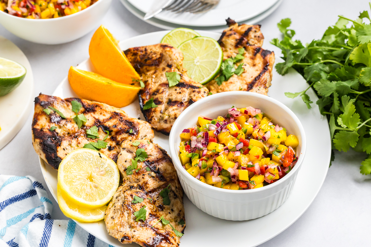 angled shot of plate of grilled citrus chicken on plate with mango salsa