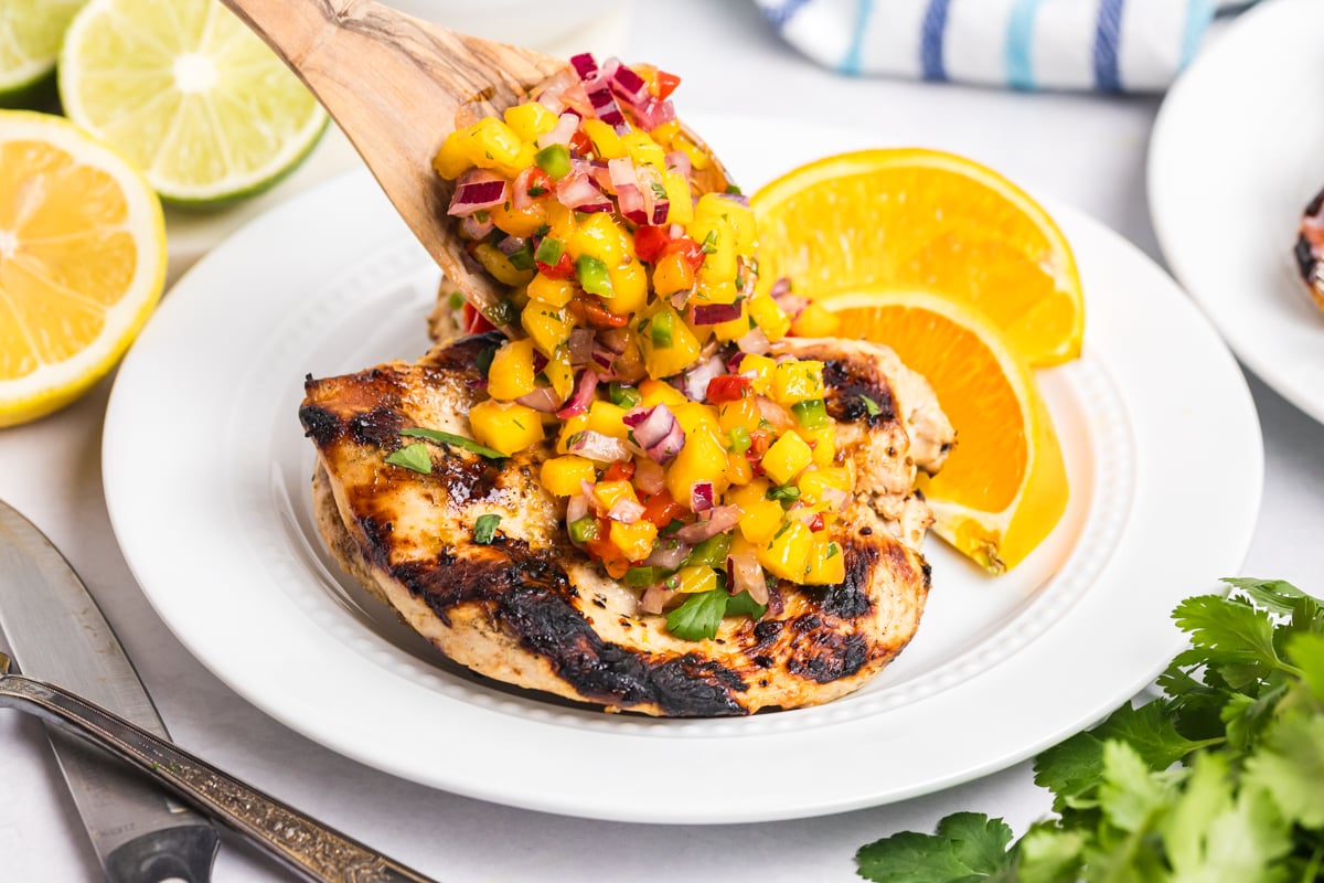 grilled citrus chicken breasts with mango salsa on white plate
