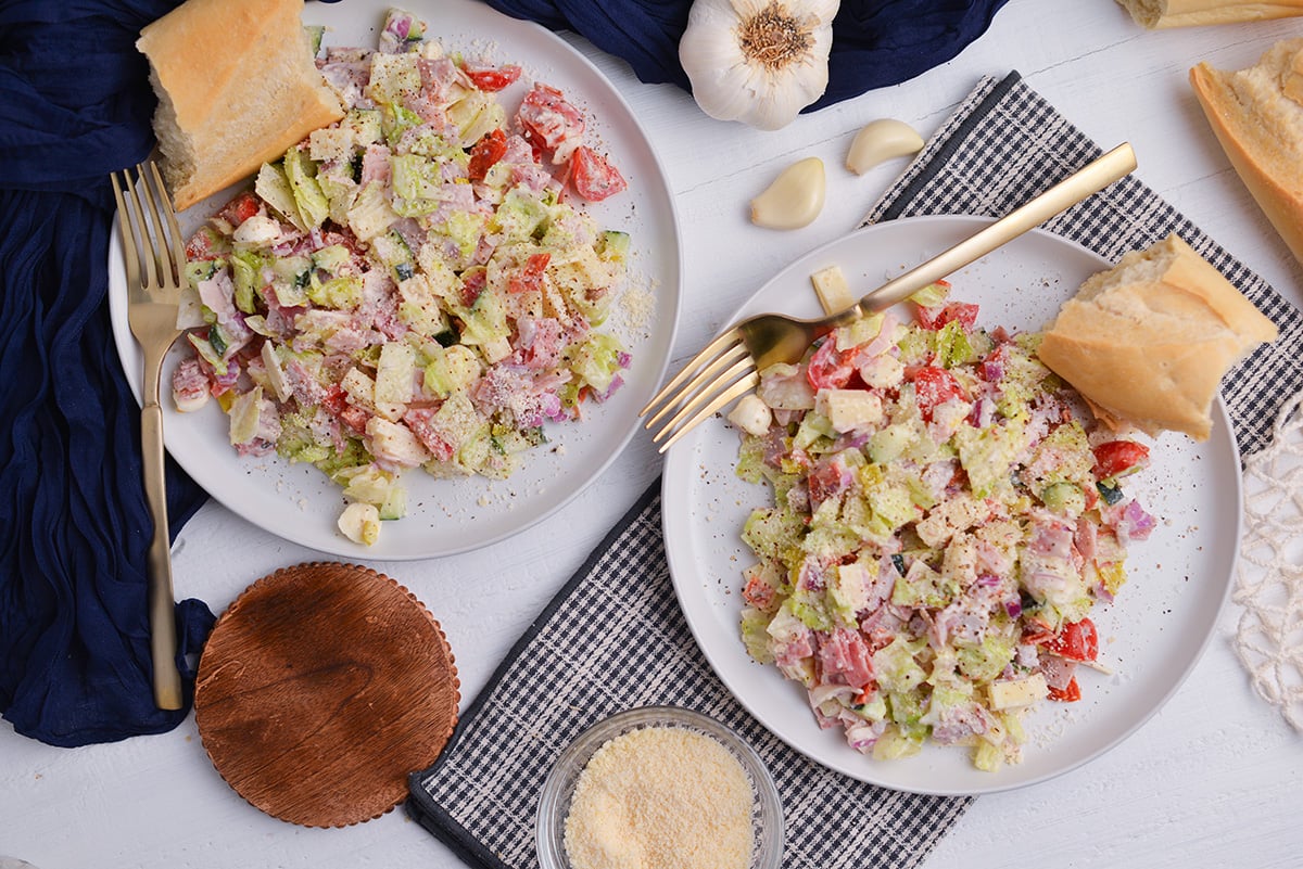 overhead shot of two white plates of salad
