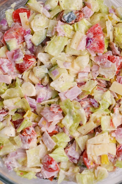 italian grinder salad in large glass bowl with deli meat and pepperoncini