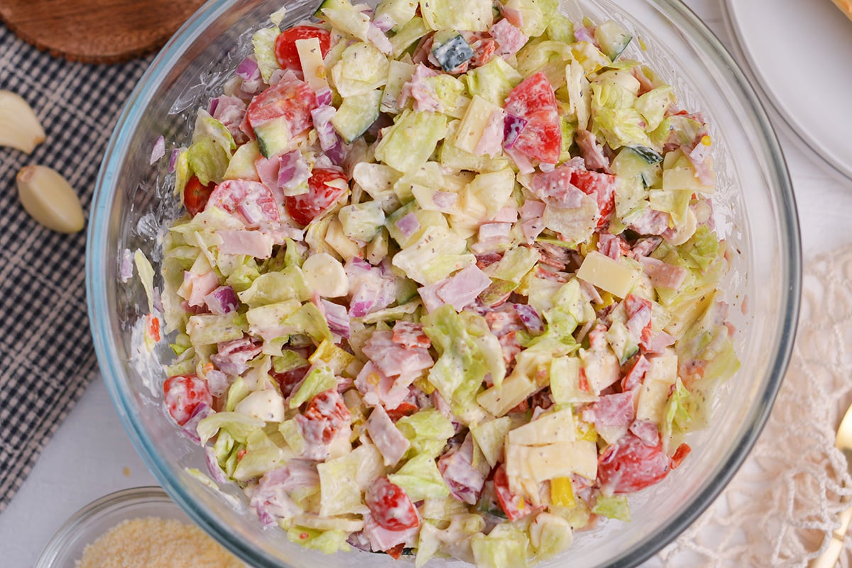 italian grinder salad in large glass bowl with deli meat and pepperoncini