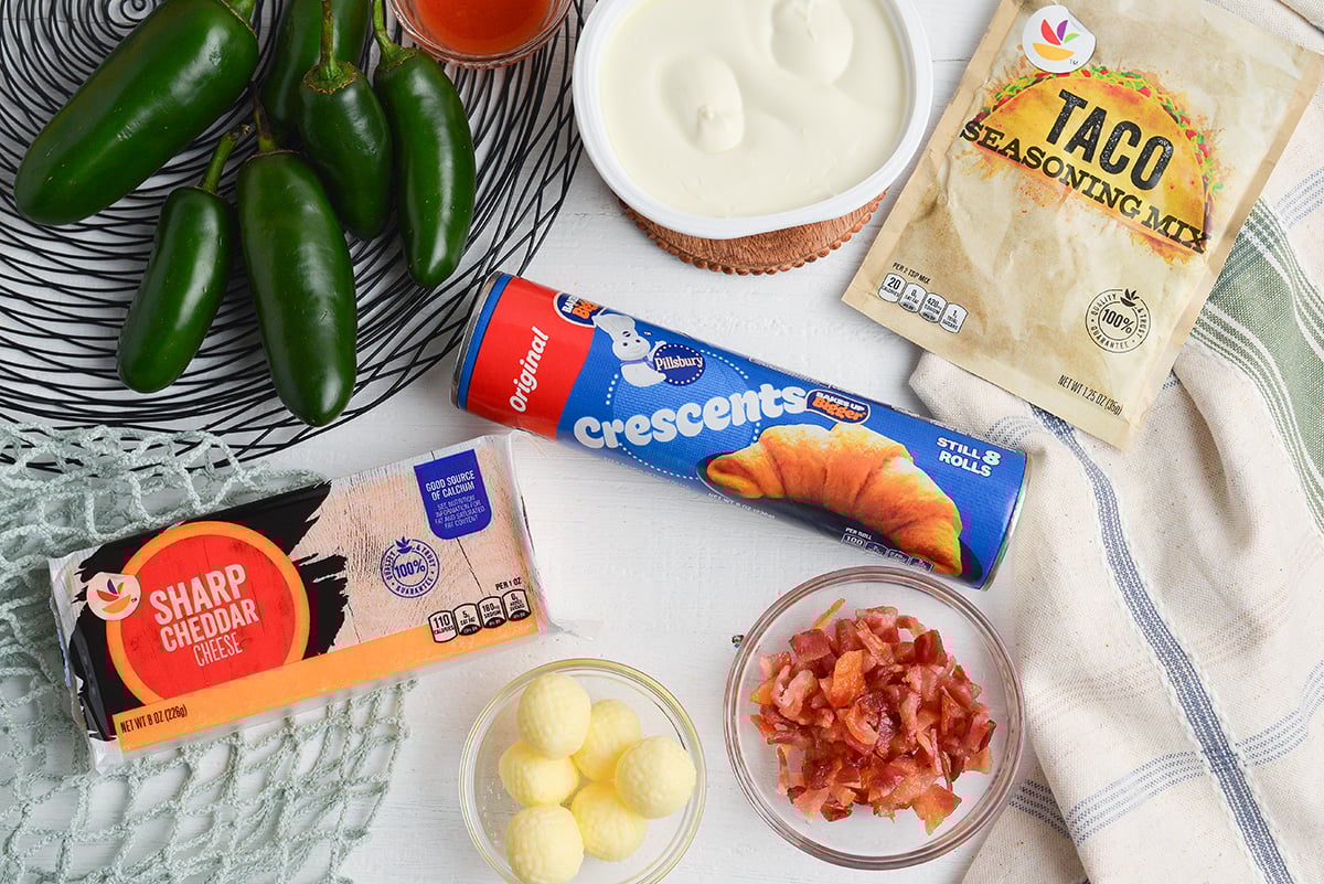 Ingredients for jalape&ntilde;o popper puffs including crescent dough, cream cheese, cheddar, bacon, jalape&ntilde;os, and taco seasoning